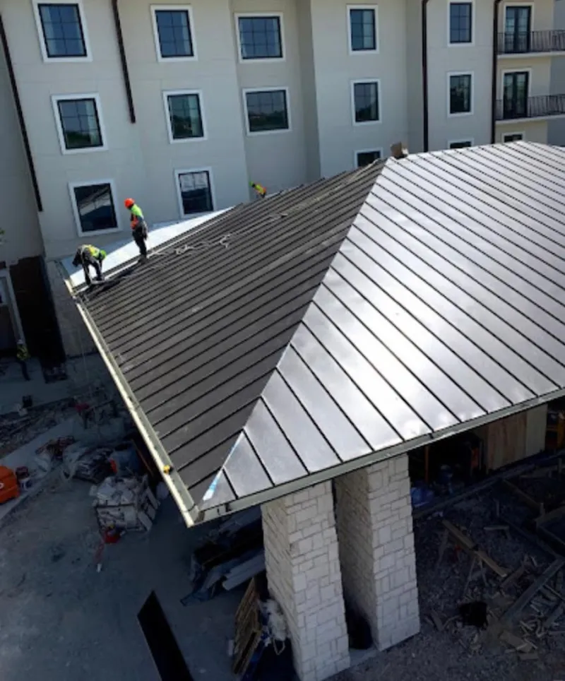 Crew installing standing seam metal roof panels on a commercial project in Eugene